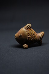 Terra cotta brown natural clay made common show piece of a cute fish isolated over black background 