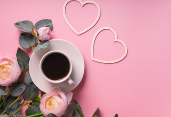 valentine's day coffee, greeting card a small white coffee mug is filled with a dark coffee, copyspace. pink flatlay background with two wooden hearts