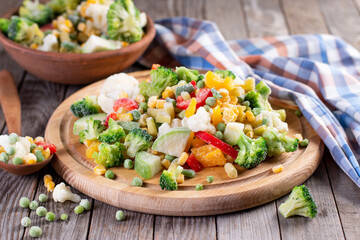 Frozen vegetables on cutting board, on wooden table background