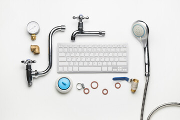 Composition with plumber's items and computer keyboard on white background