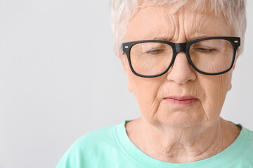 Stressed senior woman on light background