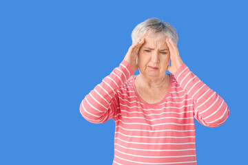 Stressed senior woman suffering from headache on color background