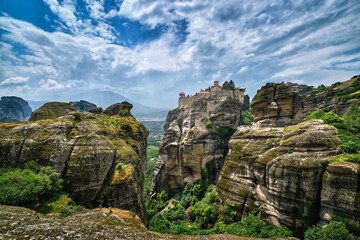Great Meteoron monastery in rocky landscape, Meteora valley, Greece, UNESCO World Heritage, mountains, rich foliage, bright spring day. Impressive sky