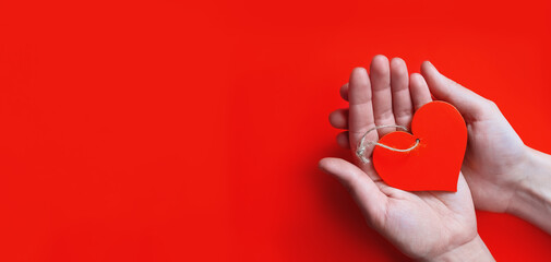 banner hands hold red heart against red background. Concept love, valentines day. with copy space....