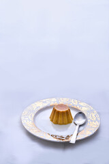 Caramel pudding kept on a plate with a silver spoon