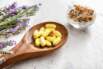Wooden spoon with plant based pills on light background