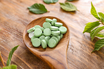 Spoon with plant based pills on wooden background