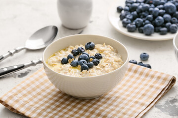 Bowl with tasty oatmeal and blueberry on table