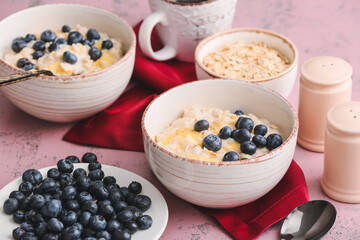 Bowls with tasty oatmeal and blueberry on table