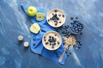 Bowls with tasty oatmeal and blueberry on color table