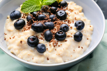 Bowl with tasty oatmeal and blueberry on table, closeup