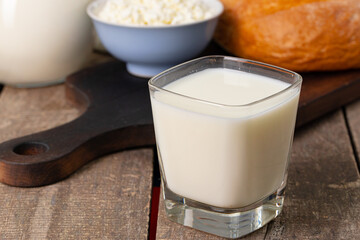Glass of milk, bowl of cottage cheese and bread on table