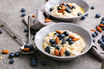 Bowls with tasty oatmeal and blueberry on table