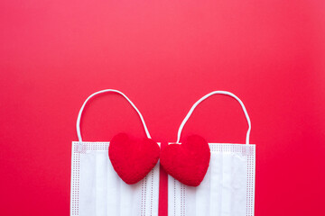 heart shape decoration and Medical face mask on red background against Coronavirus disease infection. Love, together and Happy Valentines day under Covid-19 pandemic concept