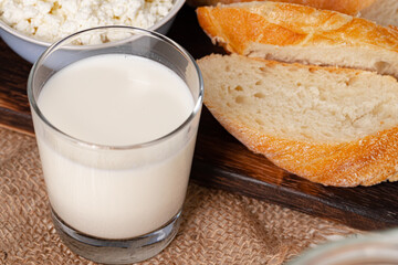 Glass of milk, bowl of cottage cheese and bread on table