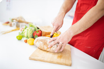 Male hands slicing bread on a cutting board