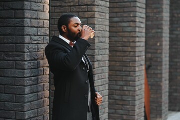 Young african american businessman drinking take away coffee at the city.