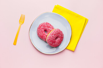 Plate with sweet donuts on color background