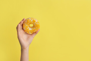 Fototapeta na wymiar Hand with sweet donut on color background