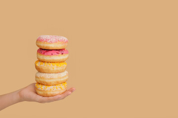 Hand with sweet donuts on color background
