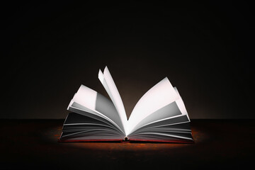 Open book on table against dark background