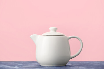 Teapot on table against color background