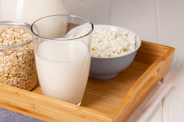 Glass of milk and oat flakes on wooden table