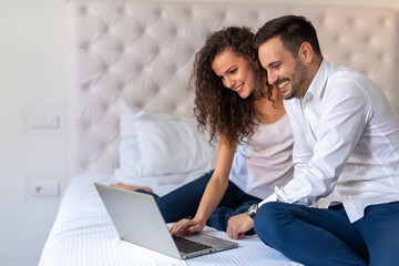 Young couple relaxing at home with laptop. Love, technology, people and fun concept.