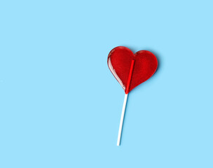 Lollipop heart on blue background. Sweet red heart shape candy on stick. symbol of love....