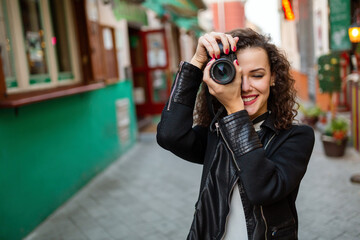 Attractive young woman talking pictures outdoors. People, travel, photographer concept.