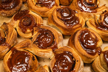 Homemade cinnamon buns with spices and caramel on parchment paper.