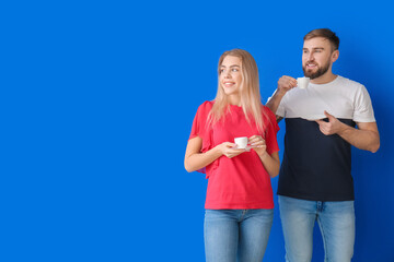 Young couple with hot coffee on color background