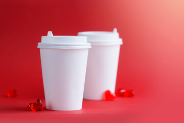 Mockup of two coffee cups on a red background with glass hearts. Layout. Horizontal format. Copyspace