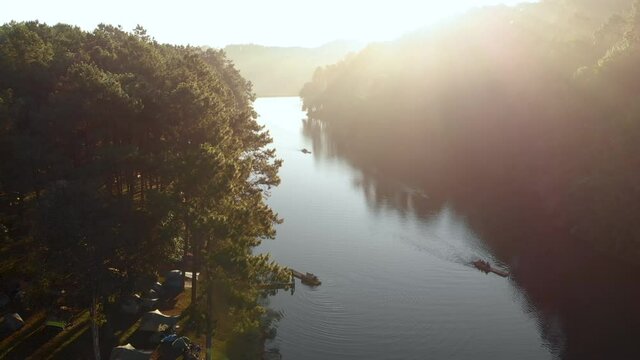 Aerial view of Morning sunlight at Pang Ung lake with camping tent, Rowing boat and lens flare of sunlight. Pang Ung a famous travel destination at Mae Hong Son province amazing Thailand. 