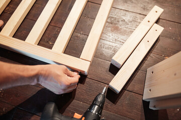 Carpenter hobbyist assembling wooden boards at home / garage.