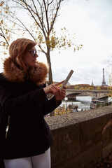 Girl using cellphone with Paris city background, Seine river and Eiffel tower.