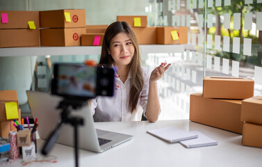 Young Asian woman entrepreneur talking camera live recording video on social network at home....