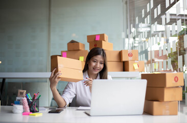 An Asian owner holds a package in a brown box, ready for delivery to a customer who orders online. As he sat in the home office