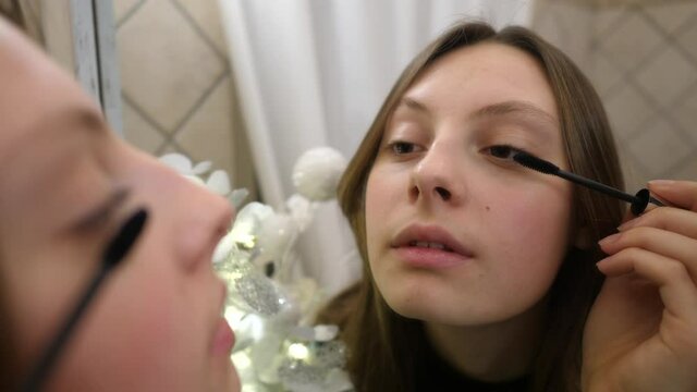 Ragazza adolescente si trucca davanti allo specchio