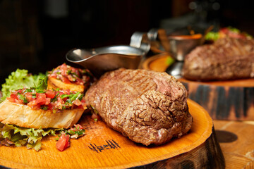 Grilled Veal steak with tomato salsa on a wooden plate. Close-up, selective focus