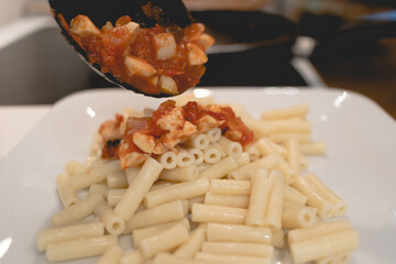 Homemade pasta with tomato sauce in a white dish.