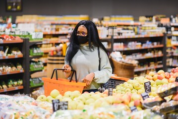 African woman wearing disposable medical mask shopping in supermarket during coronavirus pandemia outbreak. Epidemic time.