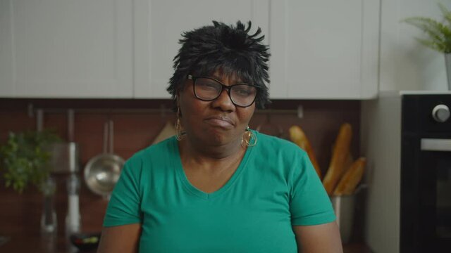 Portrait of pensive displeased mature african american woman in eyeglasses with pouting lips, deep in thoughts looking with sad depressed expression, pondering about hard decisions and choices indoors