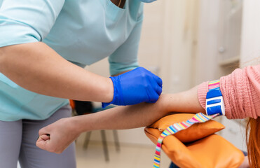 Doctor takes blood from a patient for analysis. Modern clinic with up to date equipment. Selective focus.