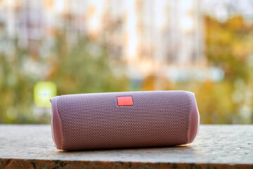 Portable pink wireless speaker in the city. Close-up, selective focus