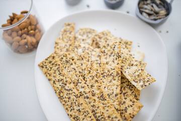 Swedish crispbread on a white plate next to almonds in a cup
