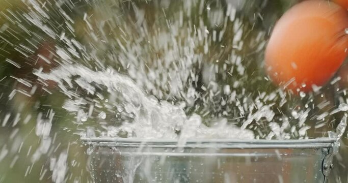 Apples of different varieties fall into a bucket of water. Slow motion video