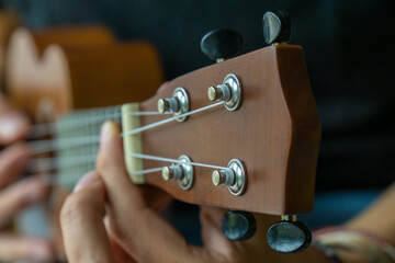 Close up of a man tuning his ukelele during a practice session