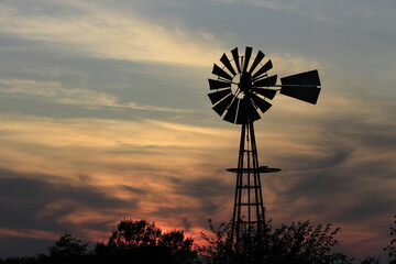 windmill at sunset with clouds north of Hutchinson Kansas USA out in the country.