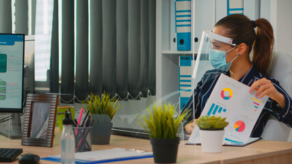 Disabled businessman sitting in wheelchair wearing face protection in prevention for coronavirus cleaning hands before checking financial data in business office. Freelancer respecting social distance